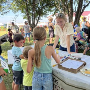 IMG_0755 2 young blonde woman in a yellow shirt shows three kids a educational project about bees.